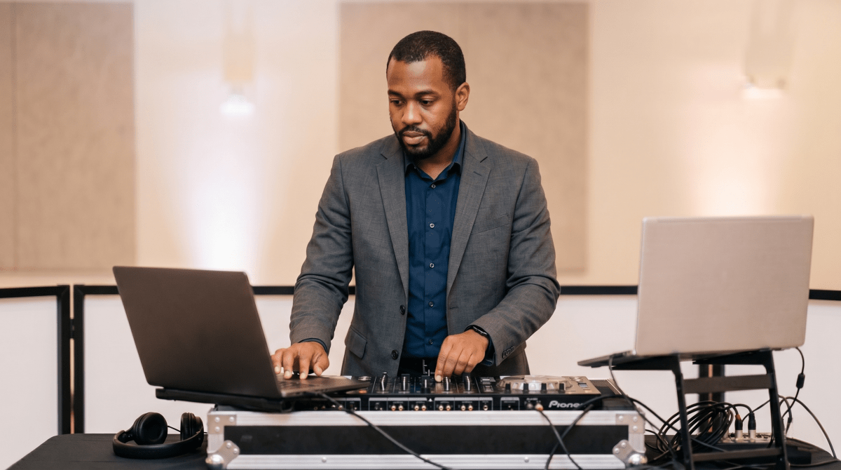 Wedding and event DJ setting up equipment and mixing music for a live celebration