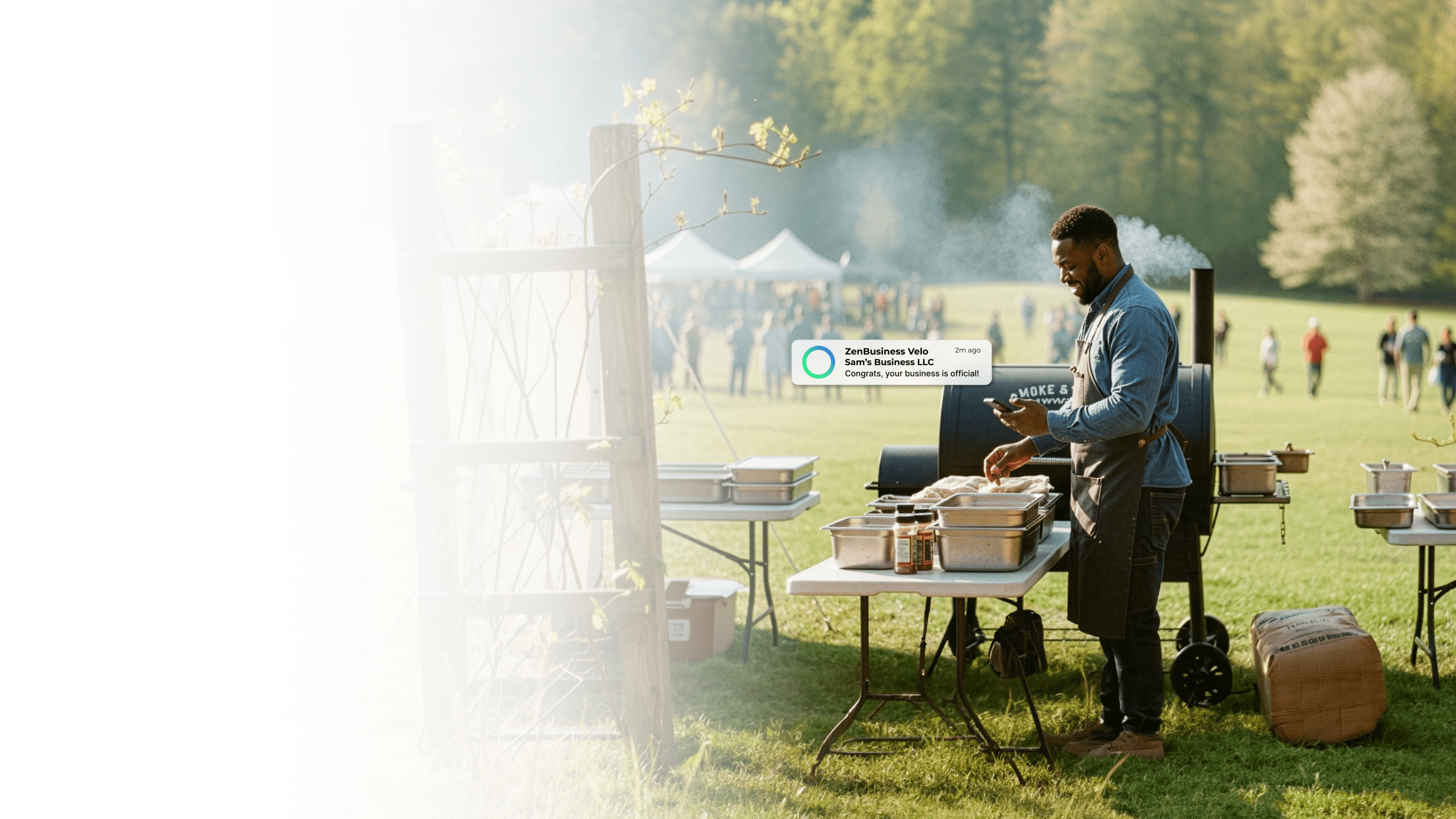 Male BBQ caterer at an outdoor North Carolina event checking his ZenBusiness Velo notification showing his LLC is officially approved