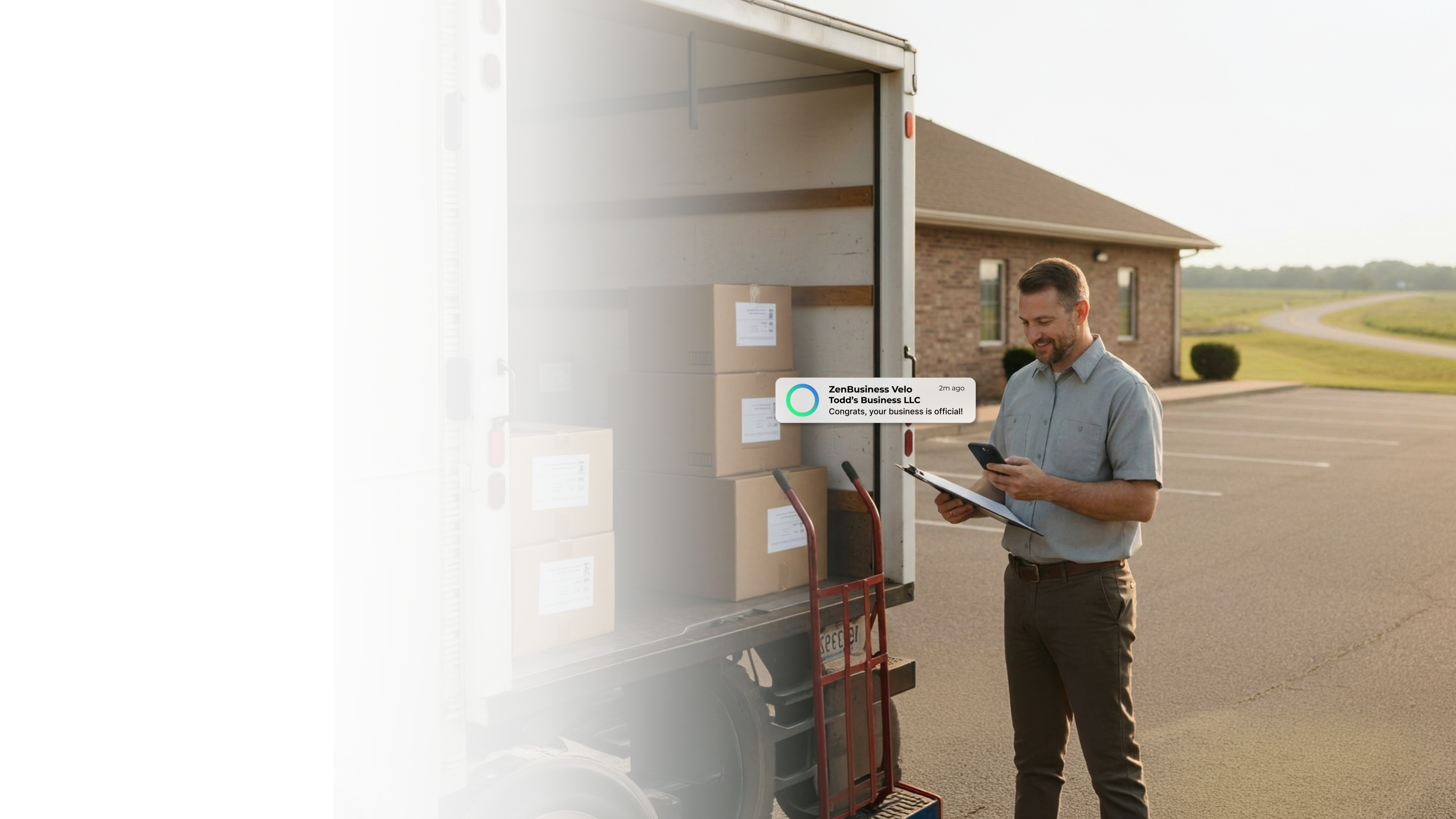 Male delivery business owner beside his loaded truck outside a brick building in Arkansas checking his ZenBusiness Velo notification that his LLC is approved