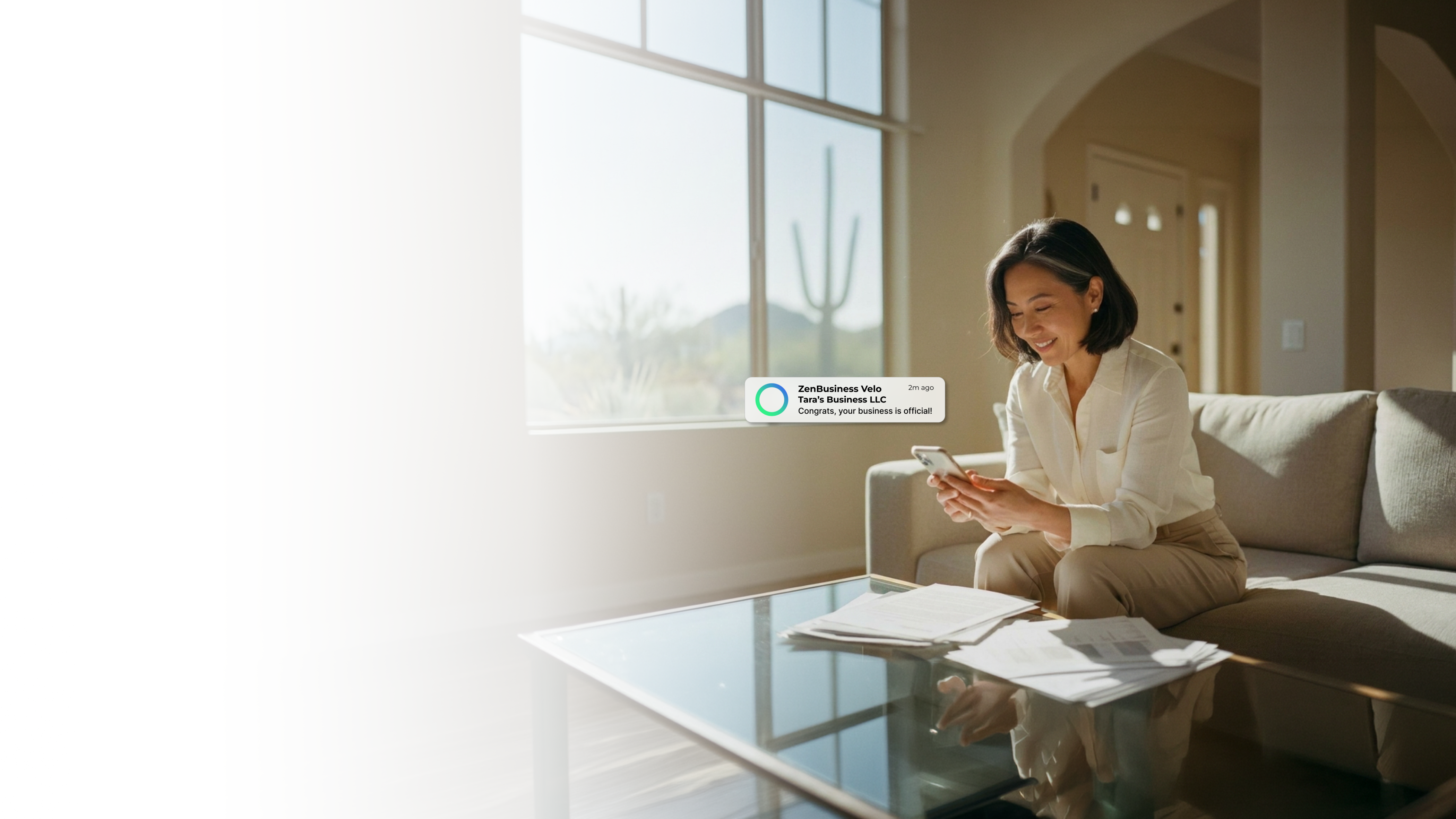Female entrepreneur at home in Scottsdale Arizona with a saguaro cactus desert view through the window checking her ZenBusiness Velo LLC approval notification