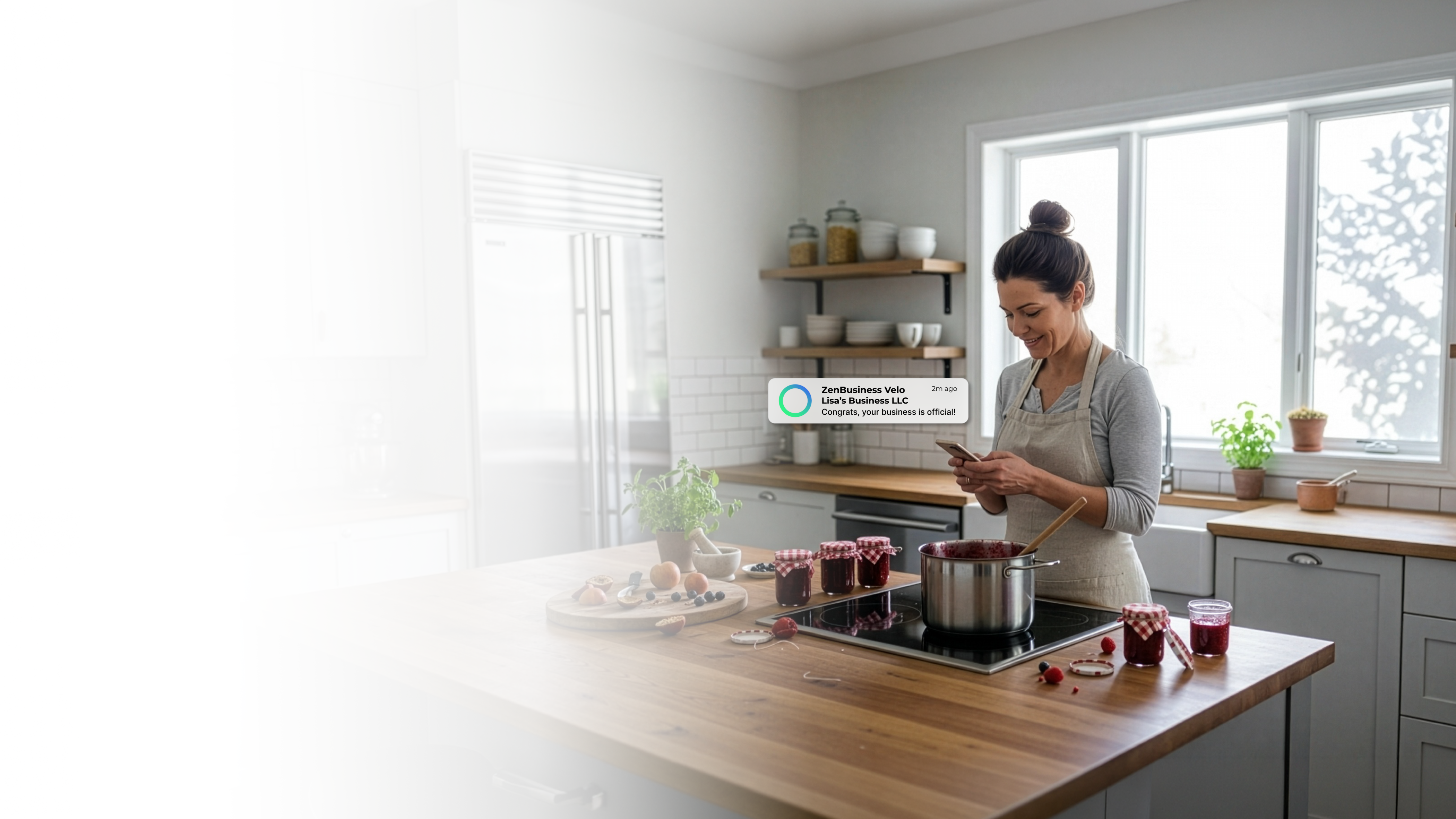 Female food entrepreneur in an Iowa home kitchen with homemade preserves on the counter checking her phone after ZenBusiness Velo confirmed her LLC is official