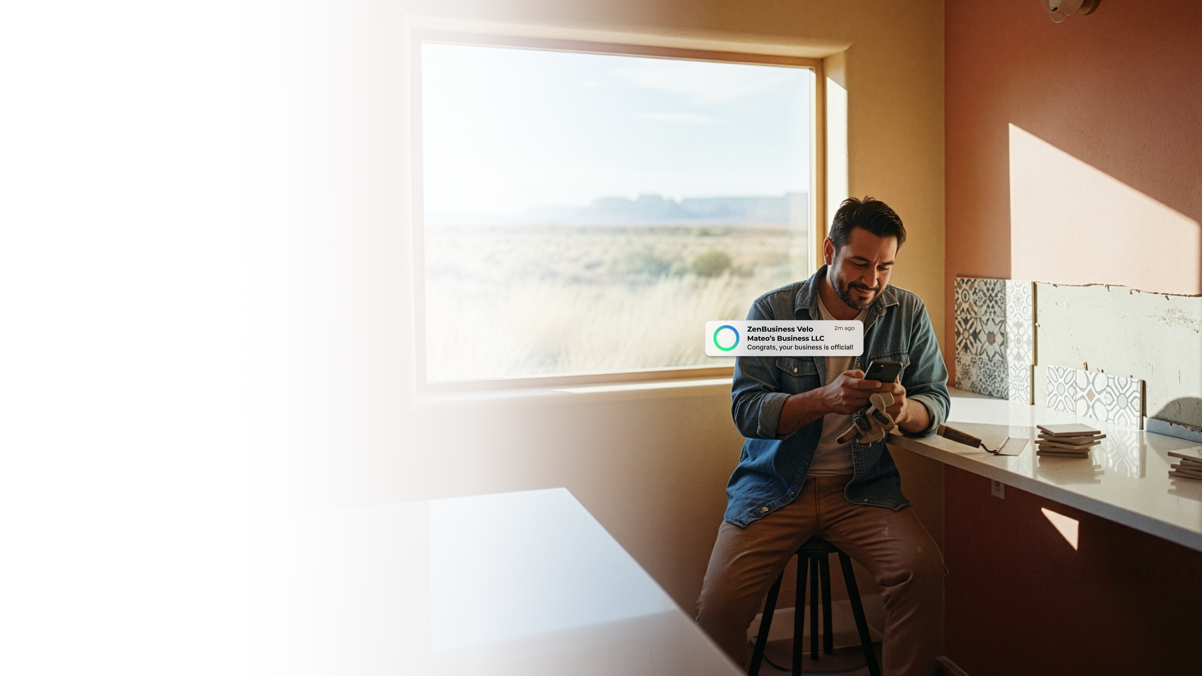 Male entrepreneur in a Santa Fe New Mexico home office checking his ZenBusiness Velo notification confirming his LLC with warm adobe walls and a sweeping desert landscape visible through the window