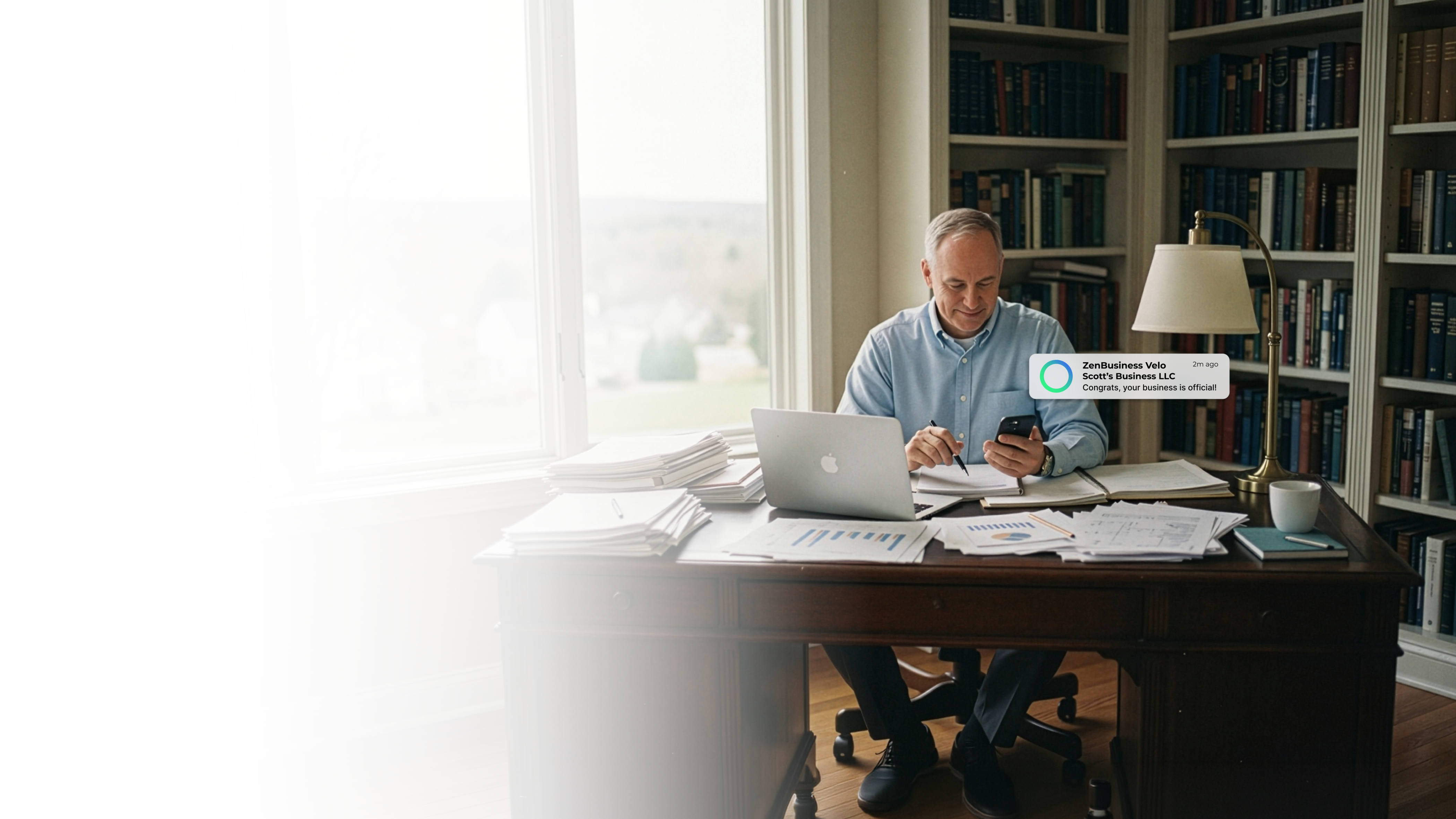 Male consultant at his Connecticut home office desk with bookshelves and natural light reading his ZenBusiness Velo notification confirming his LLC