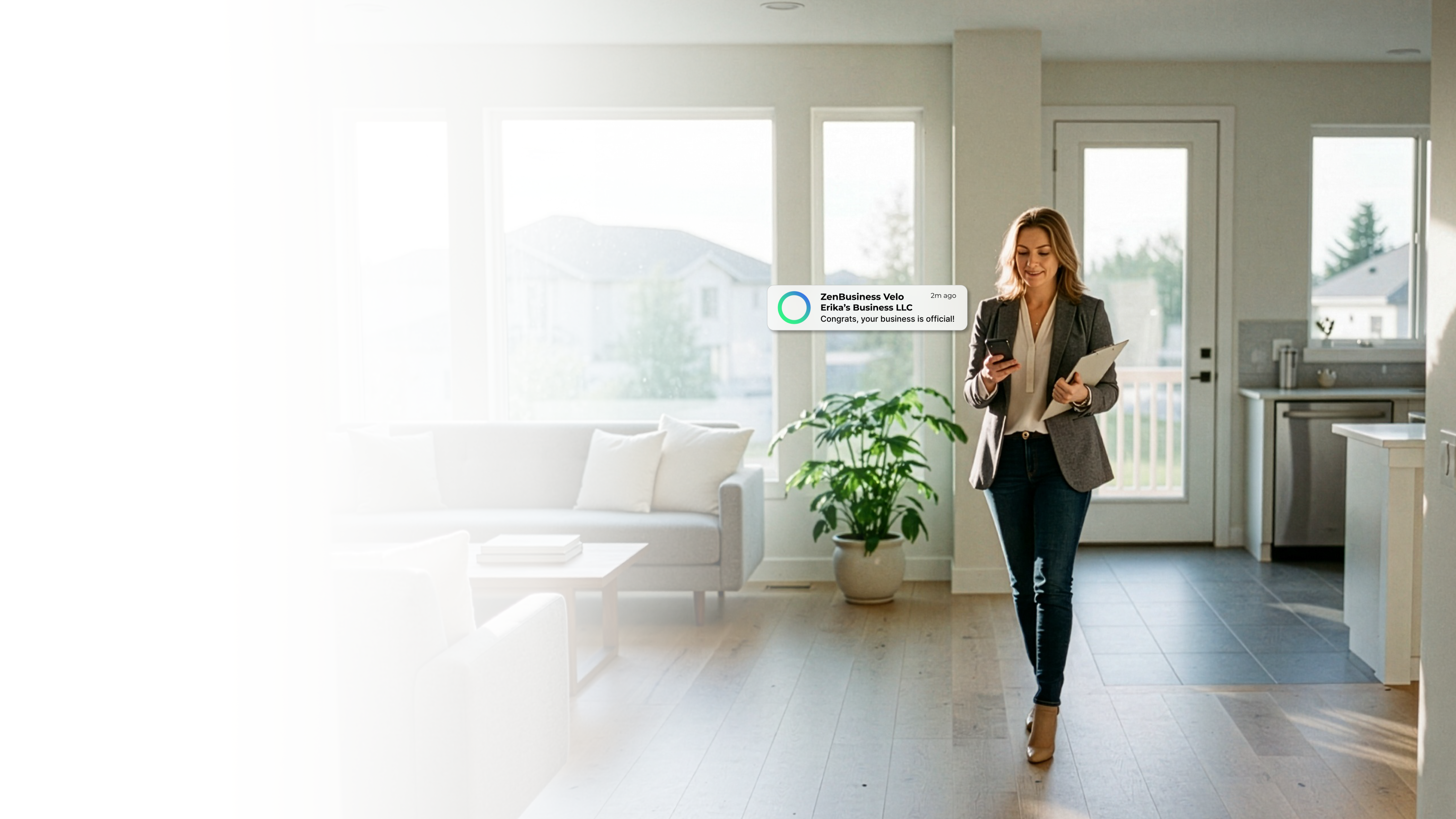 Female real estate agent inside a bright Idaho home with pine tree and mountain views checking her phone after ZenBusiness Velo confirmed her LLC
