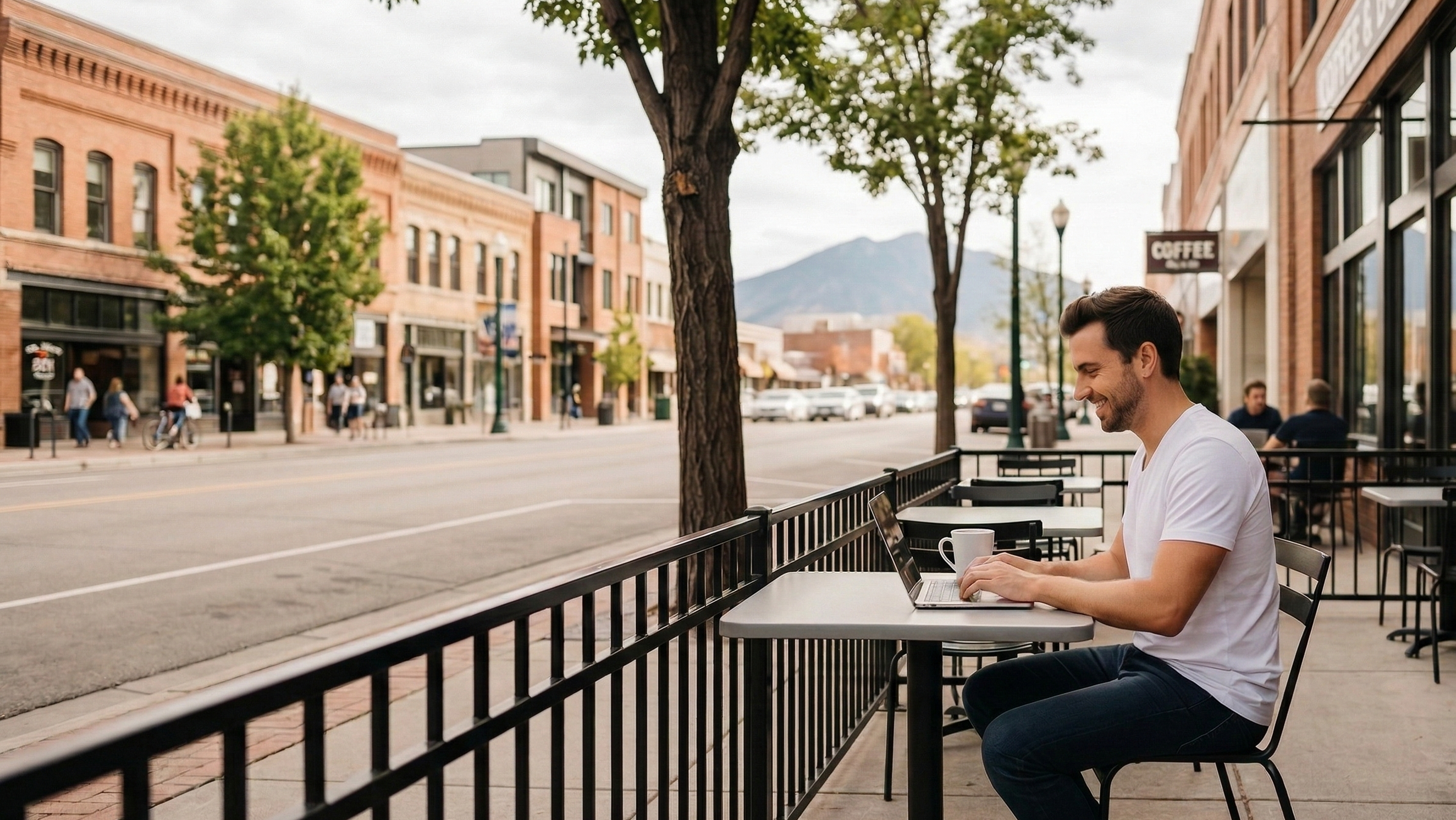 Man starting an LLC, working remotely at outdoor café in a downtown city of Idaho