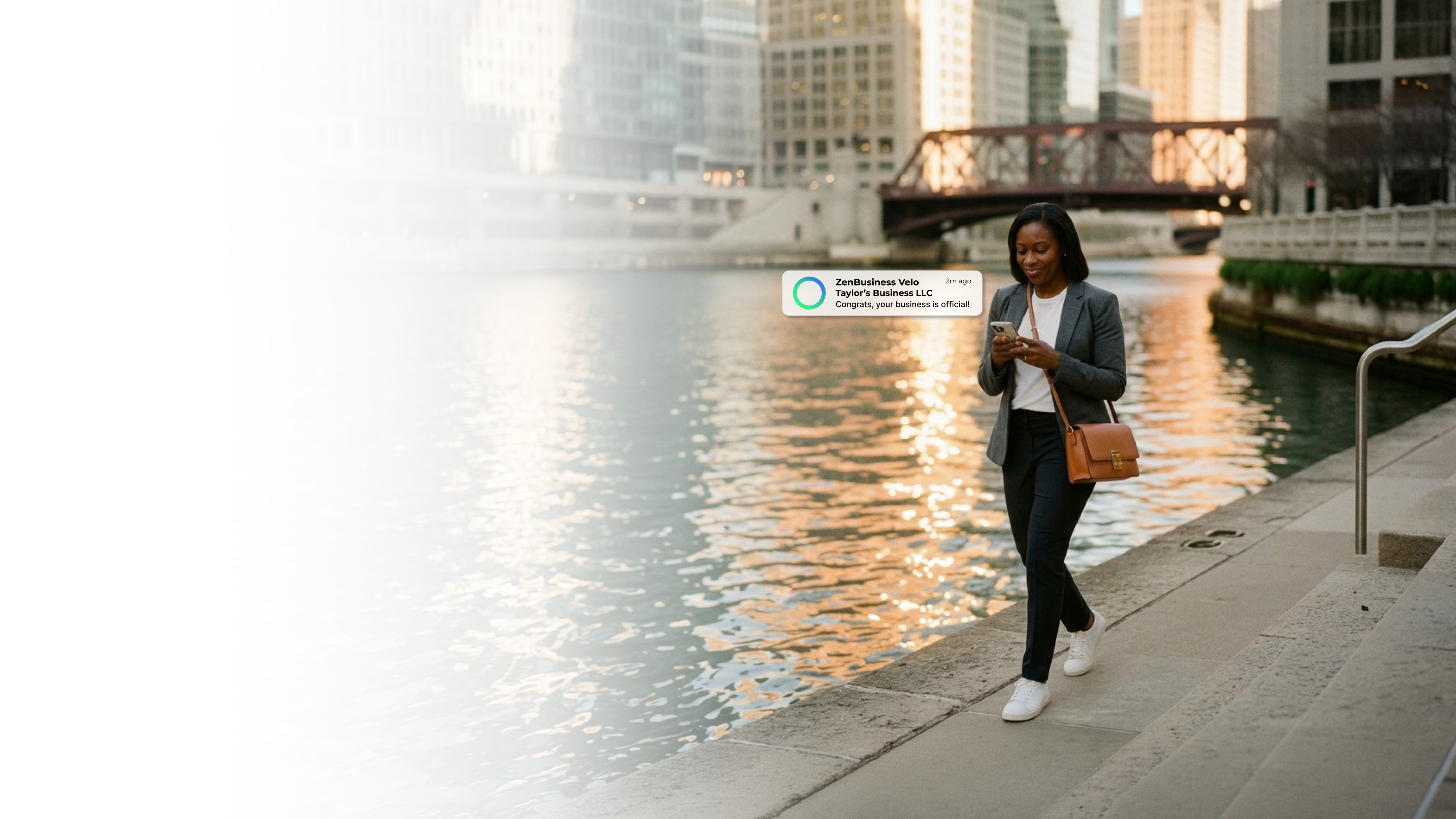 Female entrepreneur on the Chicago Illinois riverwalk at golden hour checking her ZenBusiness Velo notification that her LLC has been approved