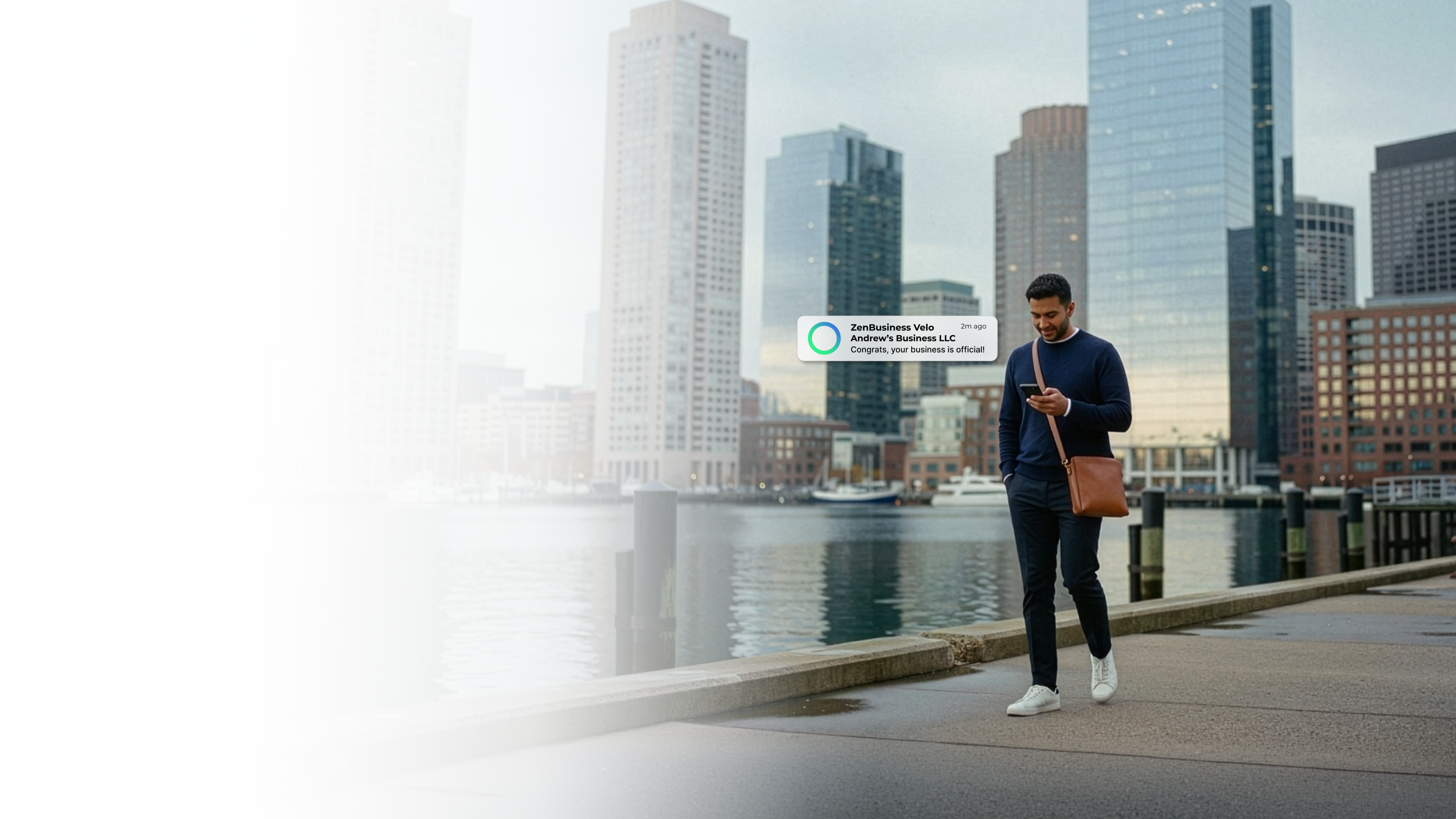 Male business owner walking along the Boston Massachusetts harbor waterfront after receiving his ZenBusiness Velo notification that his LLC is approved