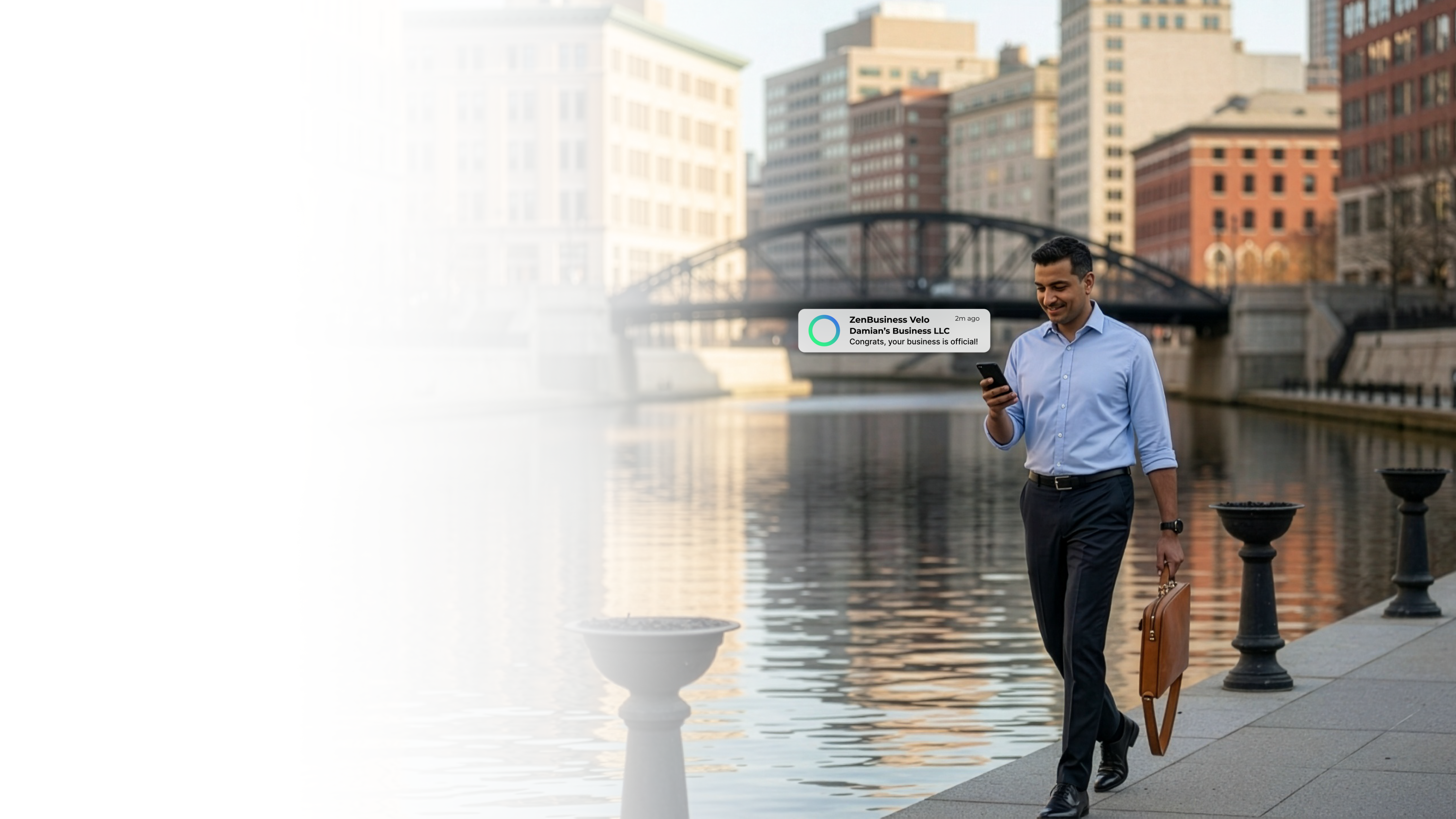 Male business professional walking along a Providence Rhode Island waterfront with an iron bridge and river reflections in the background after ZenBusiness Velo confirmed his LLC