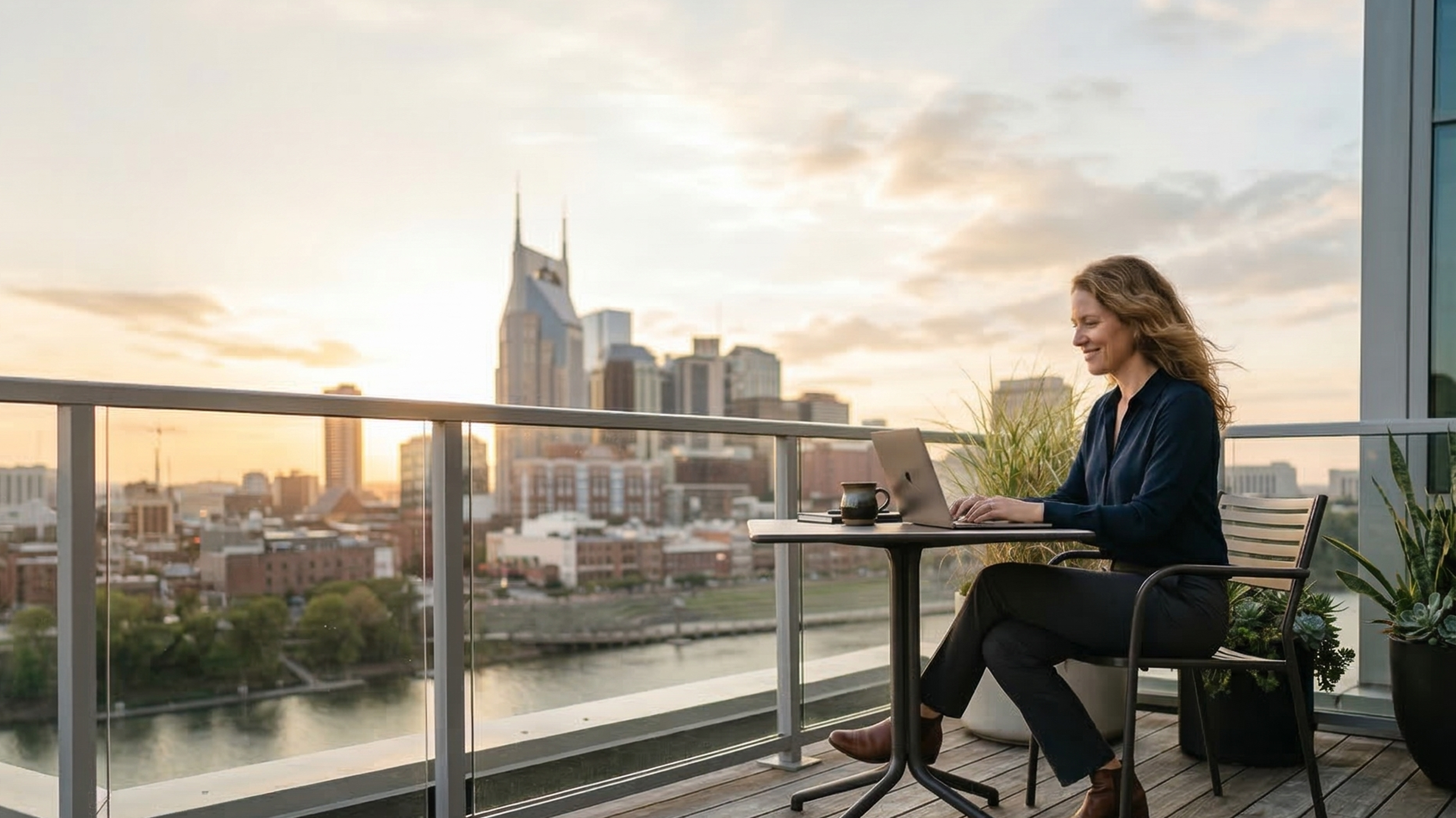 Tennessee small business owner using a laptop on a rooftop terrace in downtown Nashville