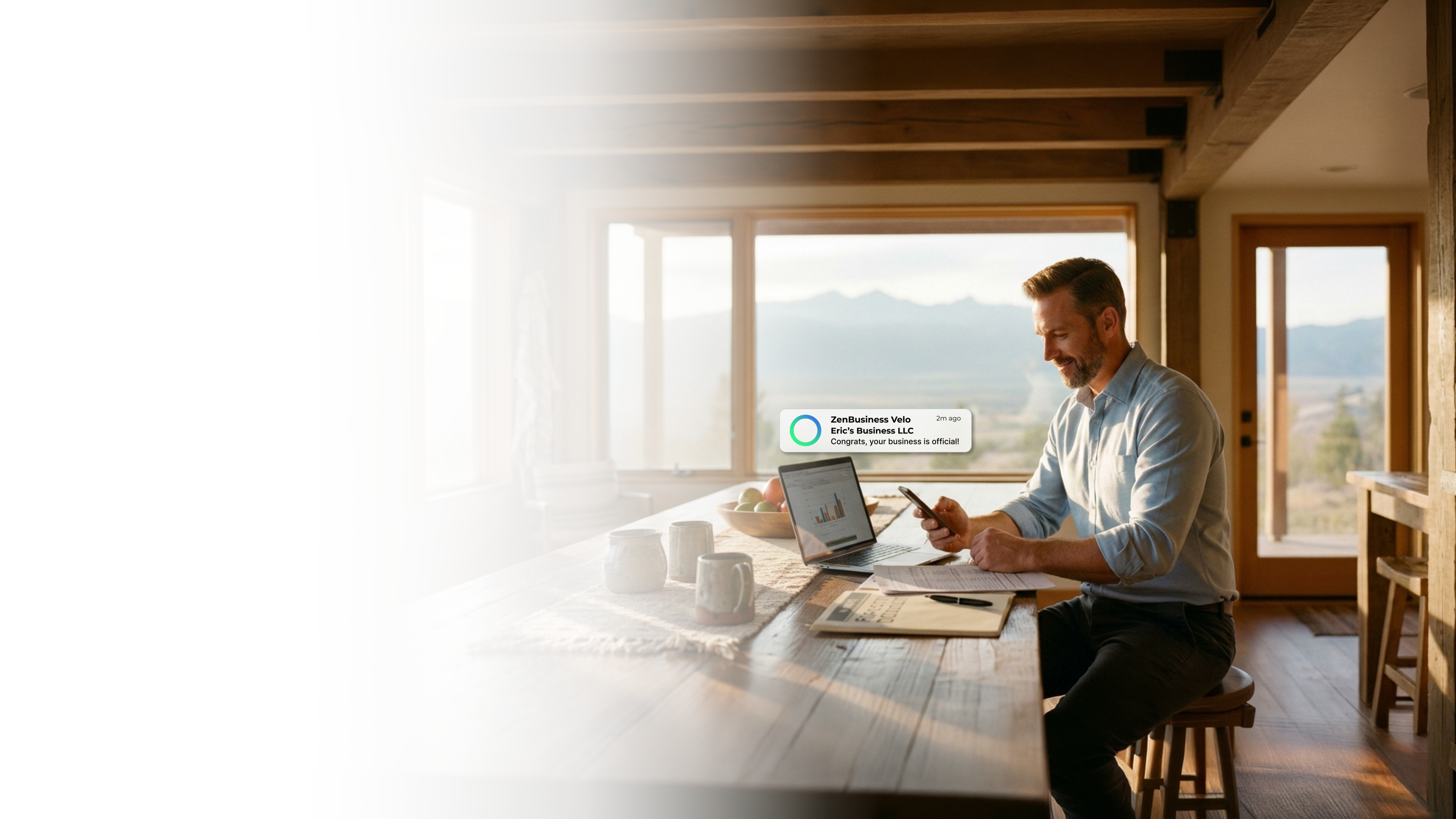 Male consultant in a modern Utah home office reading his ZenBusiness Velo notification that his LLC is approved with a laptop open to business charts and desert landscape views through large windows
