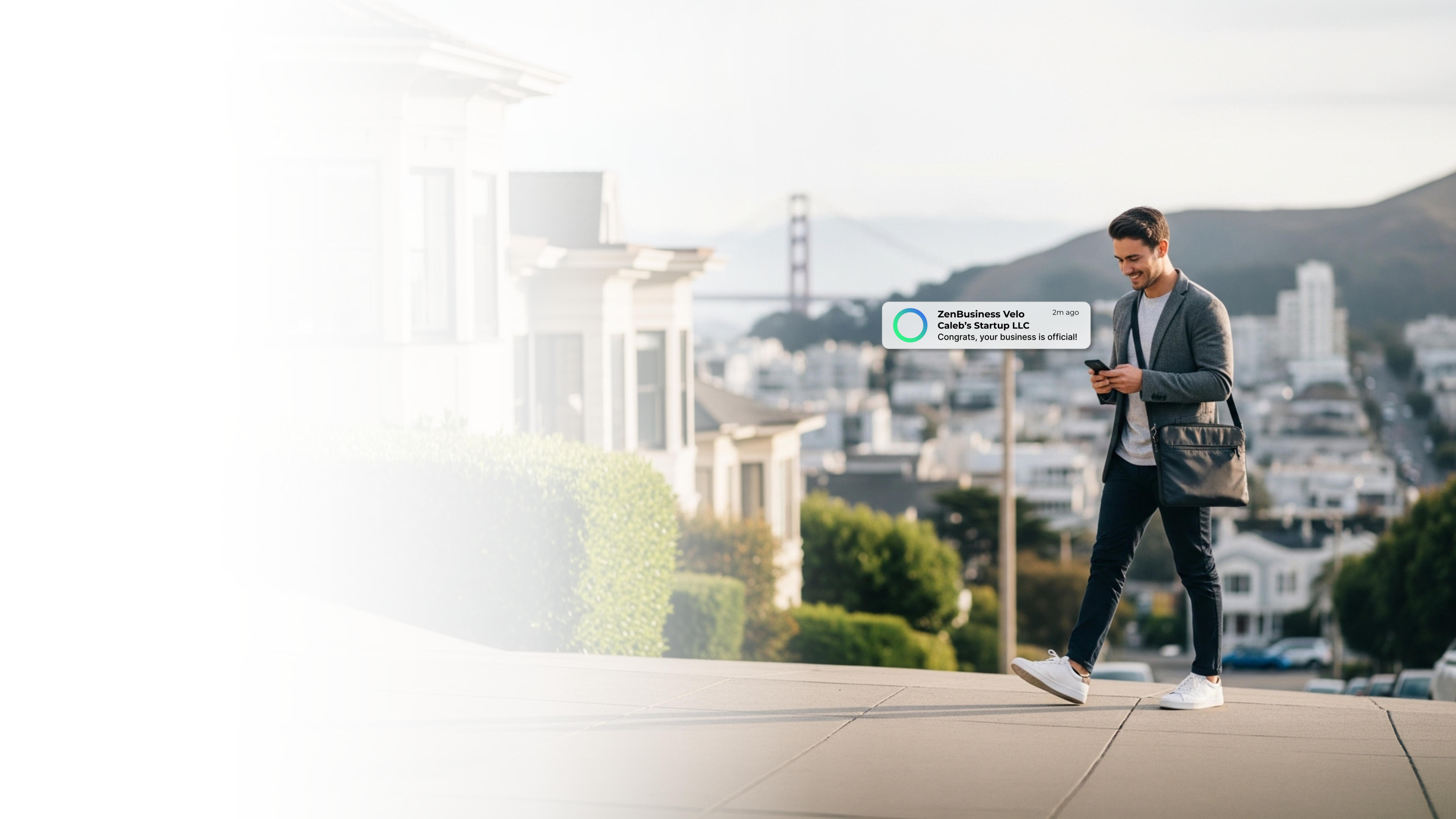 Male startup founder walking through a San Francisco California neighborhood with the Golden Gate Bridge in the background after ZenBusiness Velo confirmed his LLC