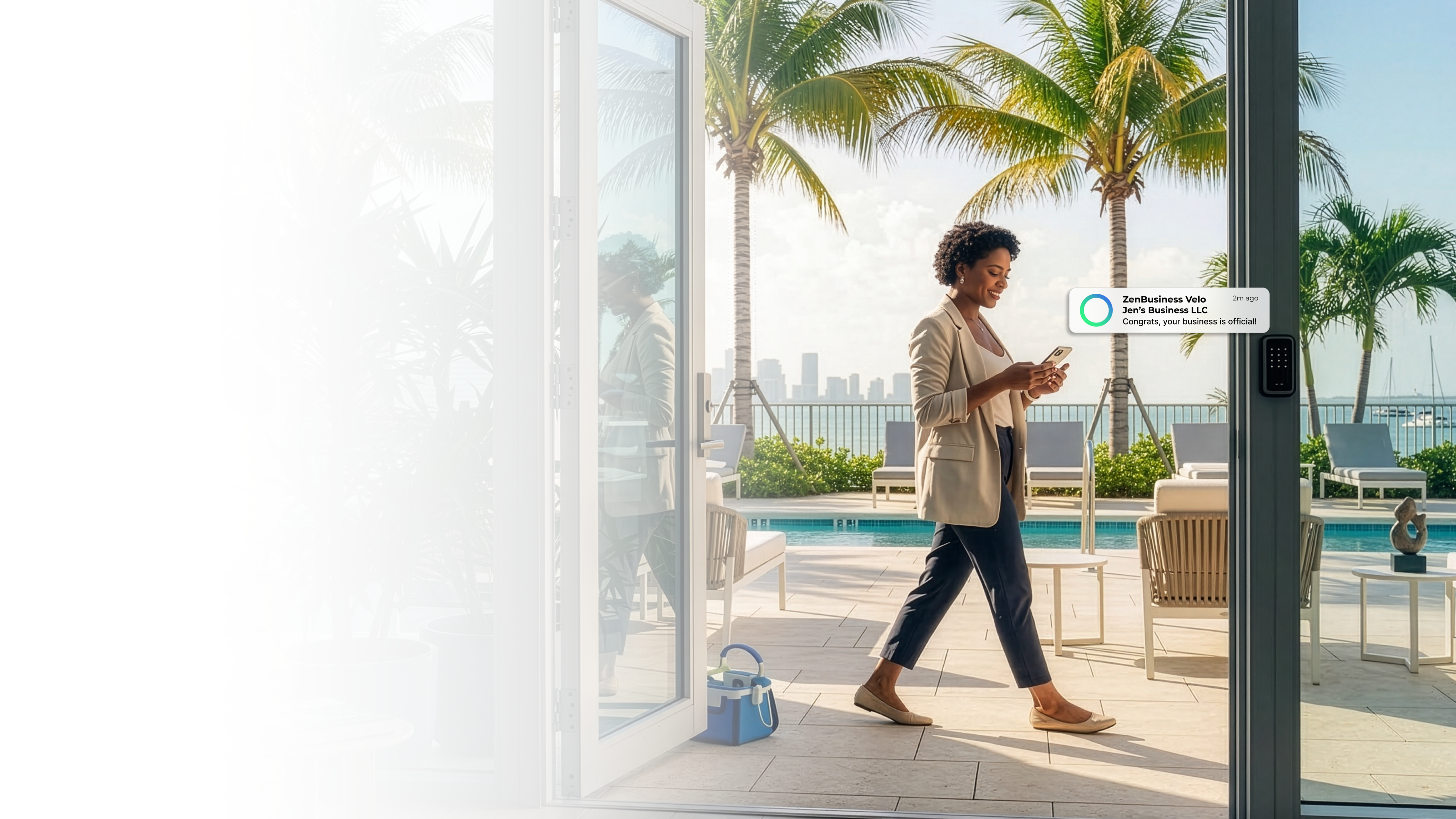 Female entrepreneur smiling at her phone near a Miami Florida waterfront with palm trees after her LLC was approved with ZenBusiness Velo