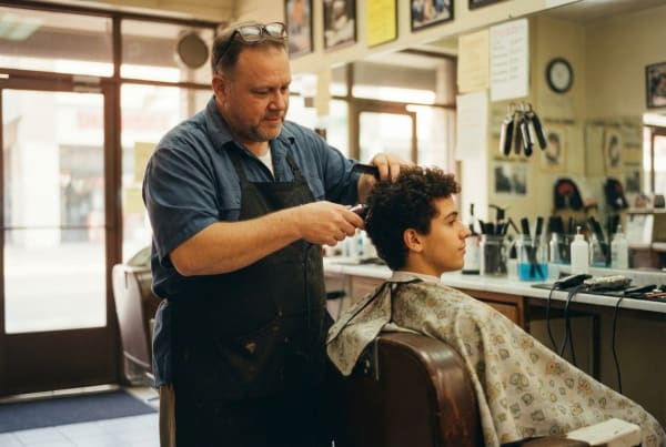 Barbershop owner cutting and grooming a client's hair at a professional barber shop