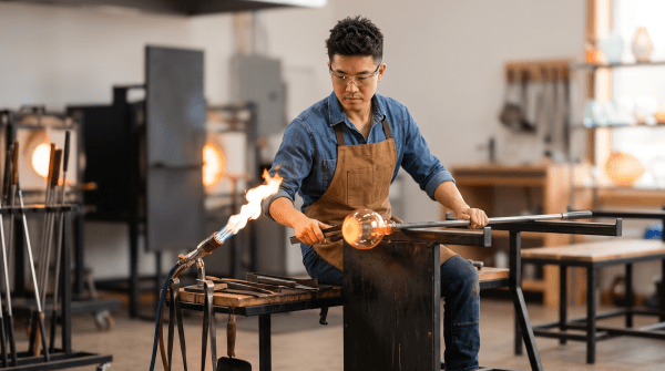 Shaping molten glass at a glass art studio workstation