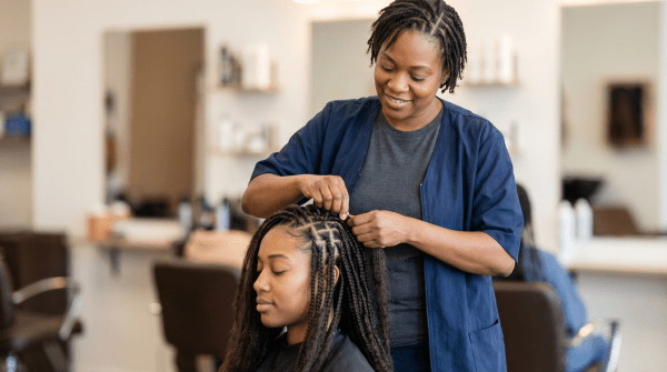 Hair braiding salon stylist creating intricate braids for a client