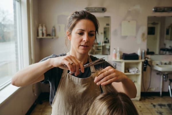 Professional hairdresser cutting and styling a client's hair at a hair salon