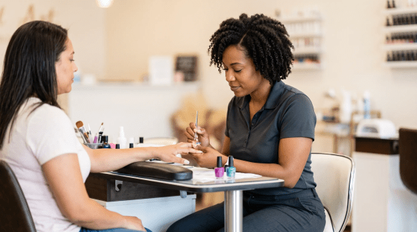 Nail art studio technician painting detailed designs on a client's nails