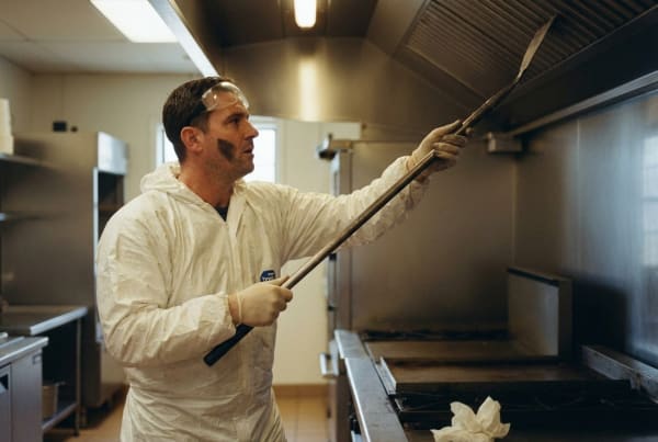 Commercial kitchen exhaust cleaning technician degreasing hood vents in a restaurant kitchen