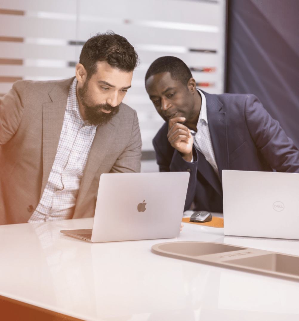 two men sit at a desk in a modern office setting
