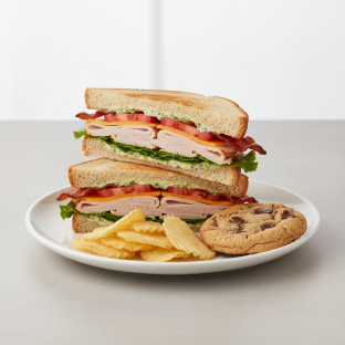 Turkey and Bacon Club Sandwich With Potato Chips and Chocolate Chip Cookie