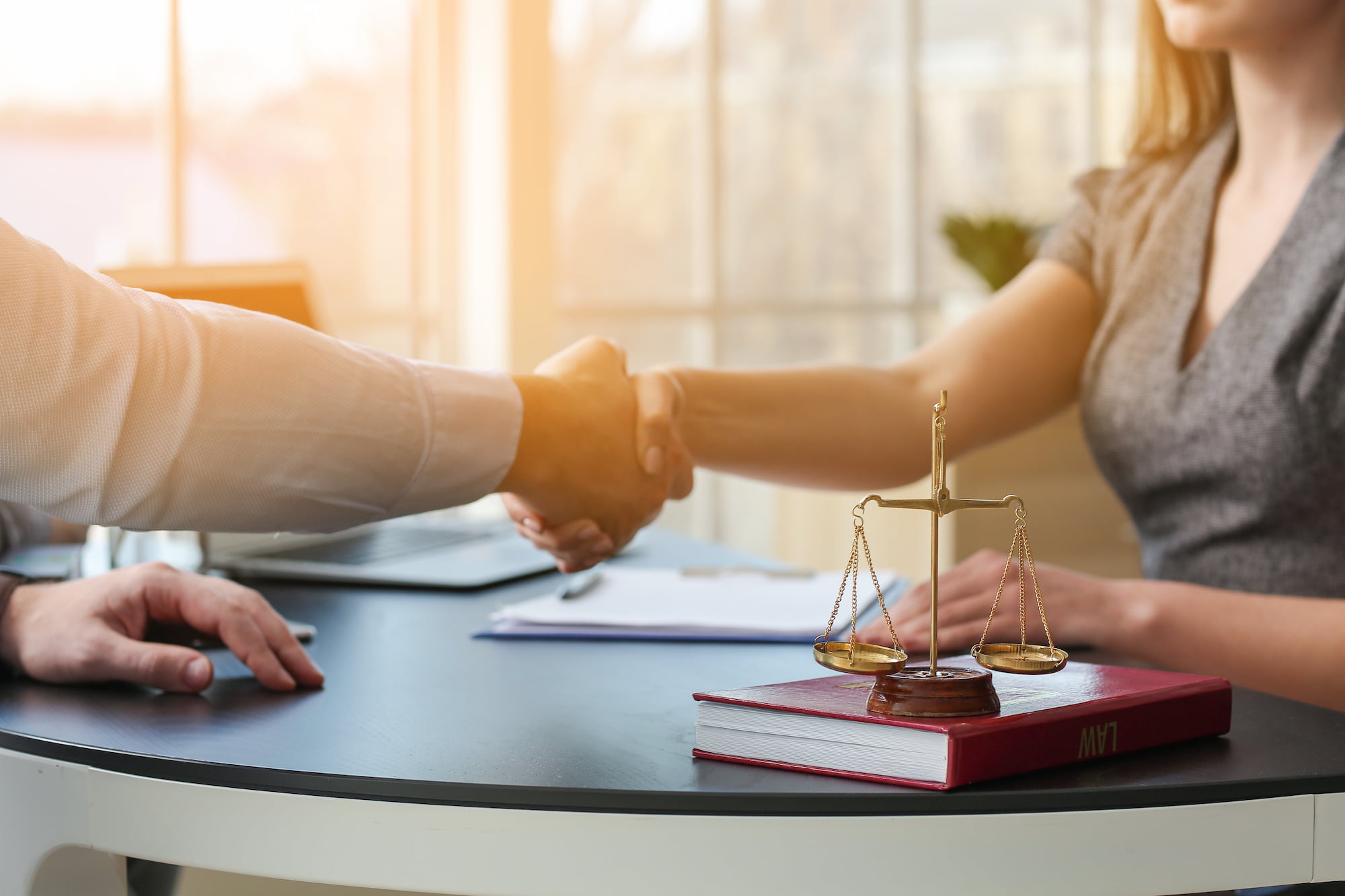 Lawyer and woman shaking hands at a desk