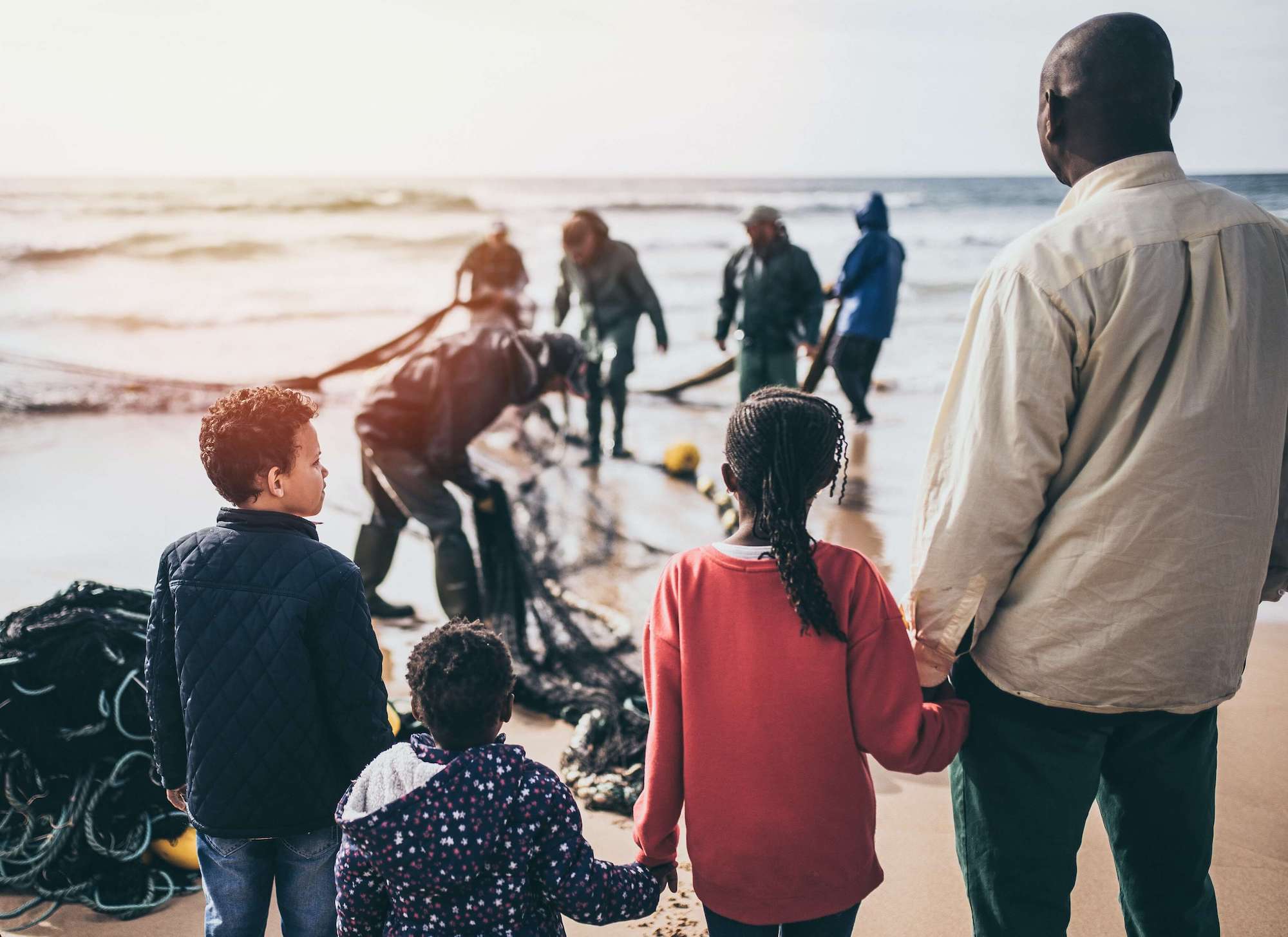 Man holding a child hands with other people on a beach