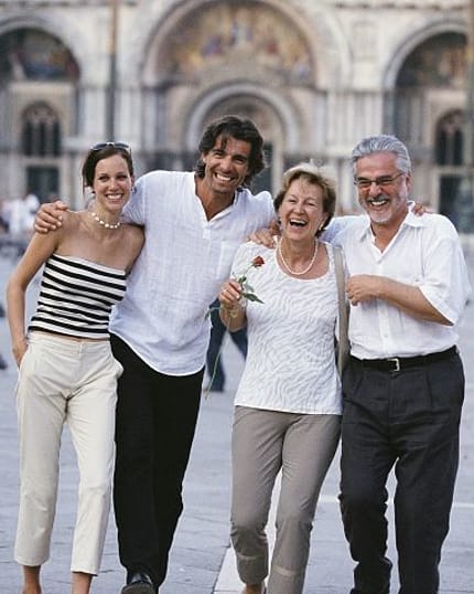 Smiling family strolls together through historic European city plaza.