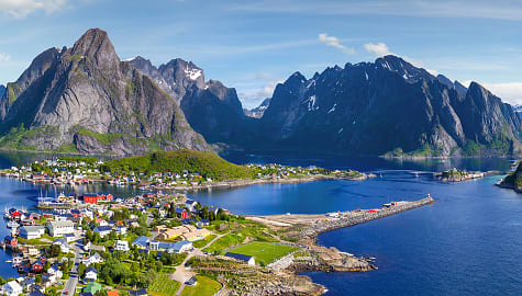 The village of Reine, Norway, under a sunny blue sky with the typical rorbu houses.