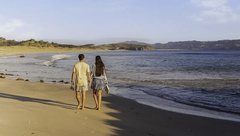 Couple walking on Tawharanui Beach in Auckland New Zealand