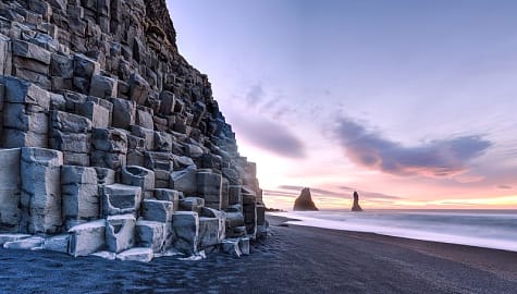 Reynisdrangar rock formations on Reynisfjara beach at sunrise, in Halsanefhellir, Iceland.