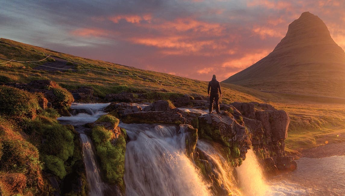 Silhouette of a man standing in front of Kirkjufoss and Kirkjufell mountain, Iceland