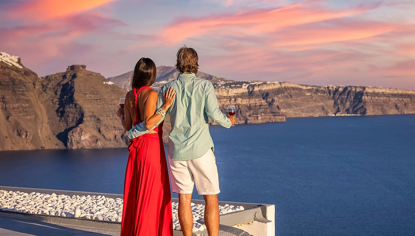Couple drinking wine and watching the sunset in Santorini, Greece