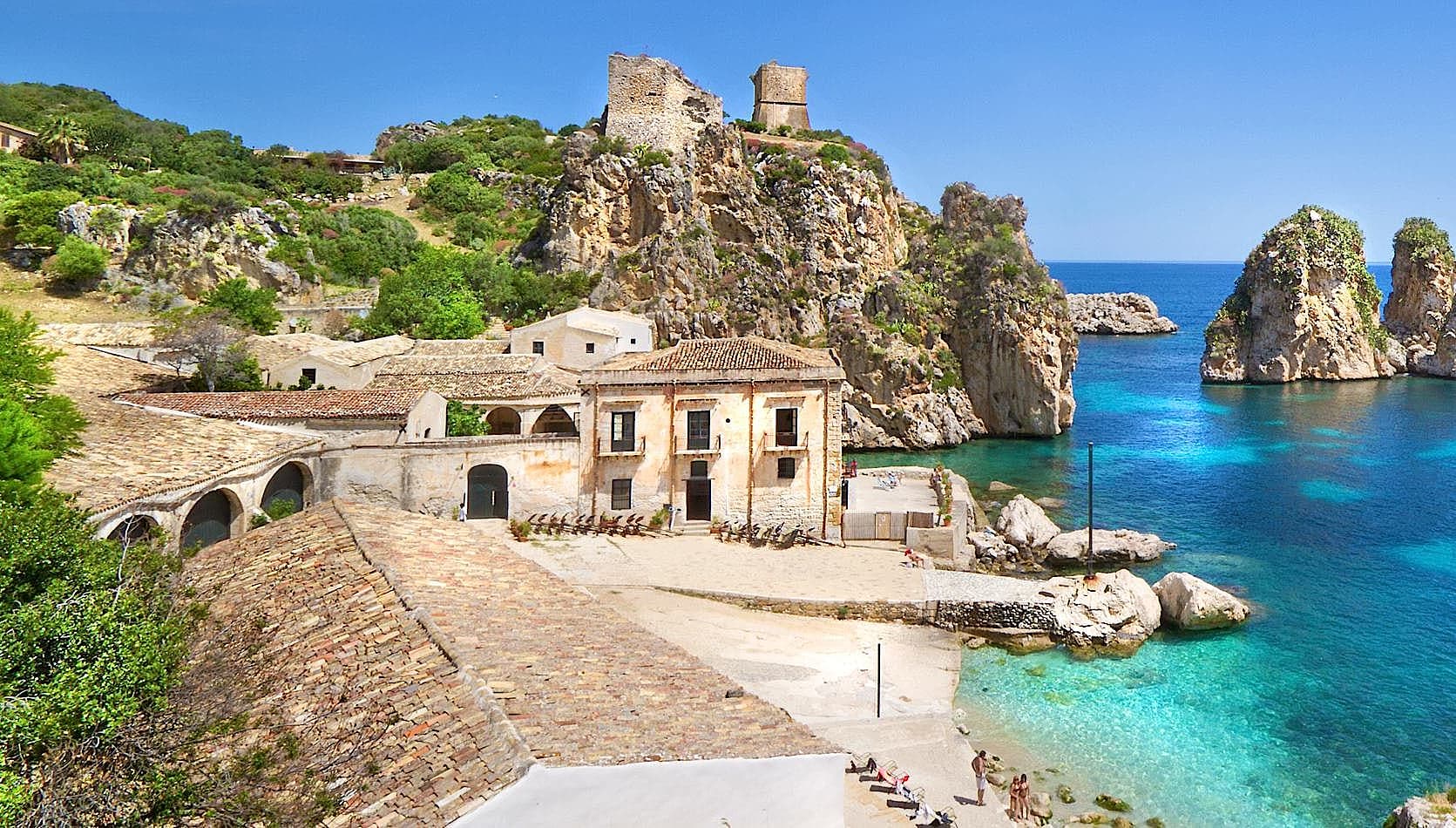 Small beach with clear blue water and rock formations at Tonnara di Scopello in Trapani, Sicily, Italy