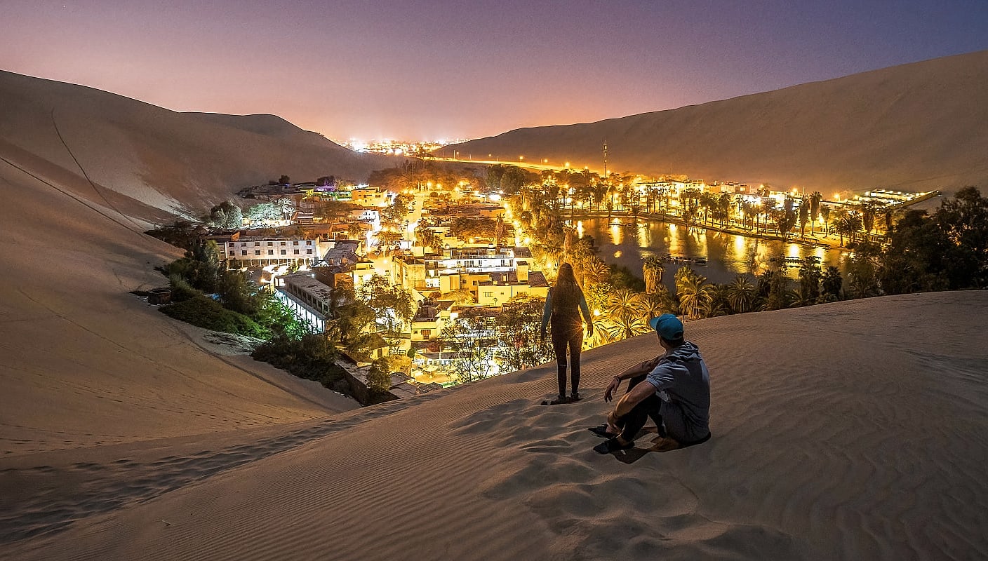 Couple on the dunes surrounding desert oasis Huacachina in southwestern Peru