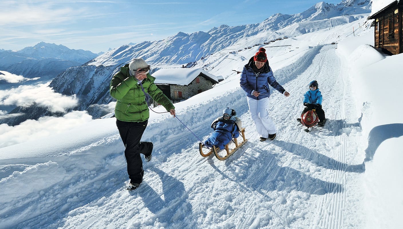 Family sledding on the Aletschbord at Belalp in Canton Valais