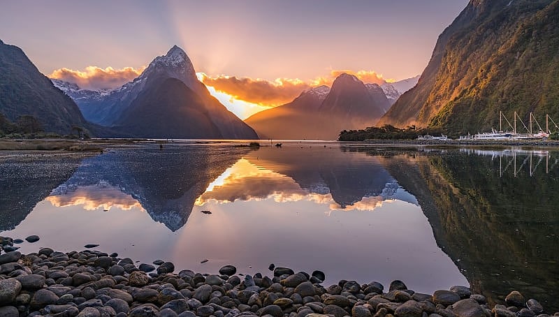 The sun behind Mitre Peak at Milford Sound in New Zealand