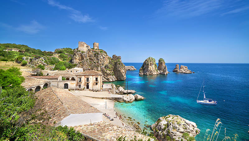 Small beach with clear blue water and rock formations at Tonnara di Scopello in Trapani, Sicily, Italy