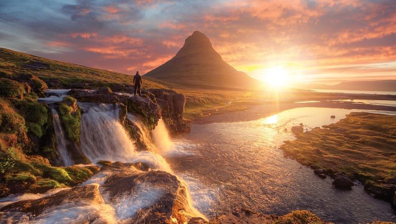 Silhouette of a man standing in front of Kirkjufoss and Kirkjufell mountain, Iceland