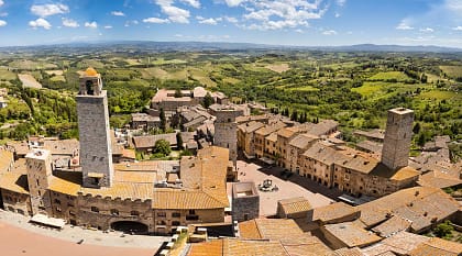 San Gimignano surrounded by the green rolling hills and vineyards of Tuscany, Italy