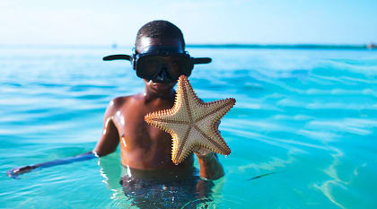Young boy shows off a starfish he found while snorkeling in Belize