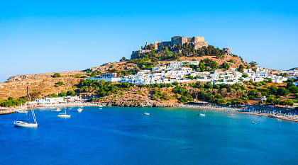 Lindos acropolis on hill above white houses and blue ocean bay in Rhodes, Greece