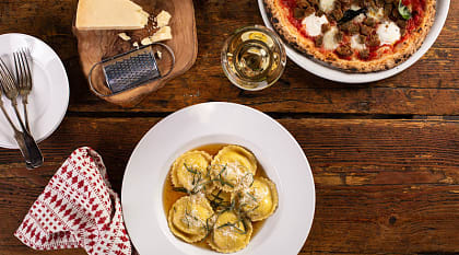 Ravioli, pizza and wine on rustic restaurant table in Italy