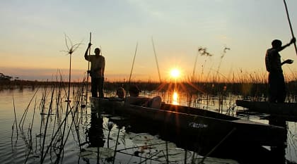 Couple on mokoro boat safari at sunset in the Okavango Delta, Botswana