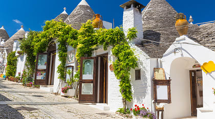 Beautiful town of Alberobello with trulli houses among green plants and flowers in the Apulia region of southern Italy.