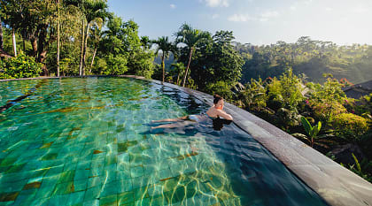 Woman lounging in an infinity pool at a luxury resort in Bali, Indonesia