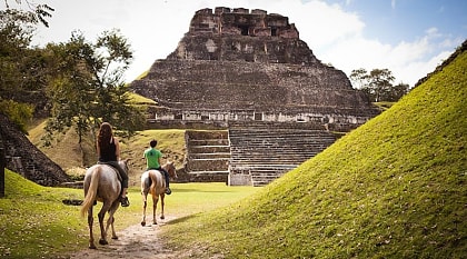 Xunantunich in Cayo District, Belize. Photo courtesy of Kaana Resort Couple horseback riding to the ancient Maya ruins of Xunantunich in Cayo District, Belize