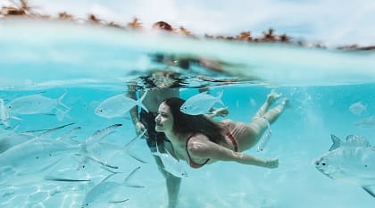 A couple swims in the ocean in the Maldives.