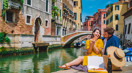 Couple enjoying a romantic picnic along a canal in Venice, Italy