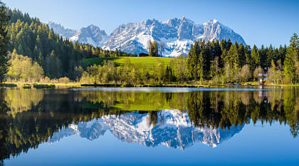 Idyllic alpine scenery, snowy mountains mirroring in a small lake in Tyrol, Austria.