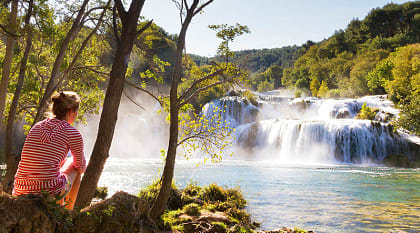 Woman traveler relaxing and viewing the waterfalls in Krka National Park, Croatia